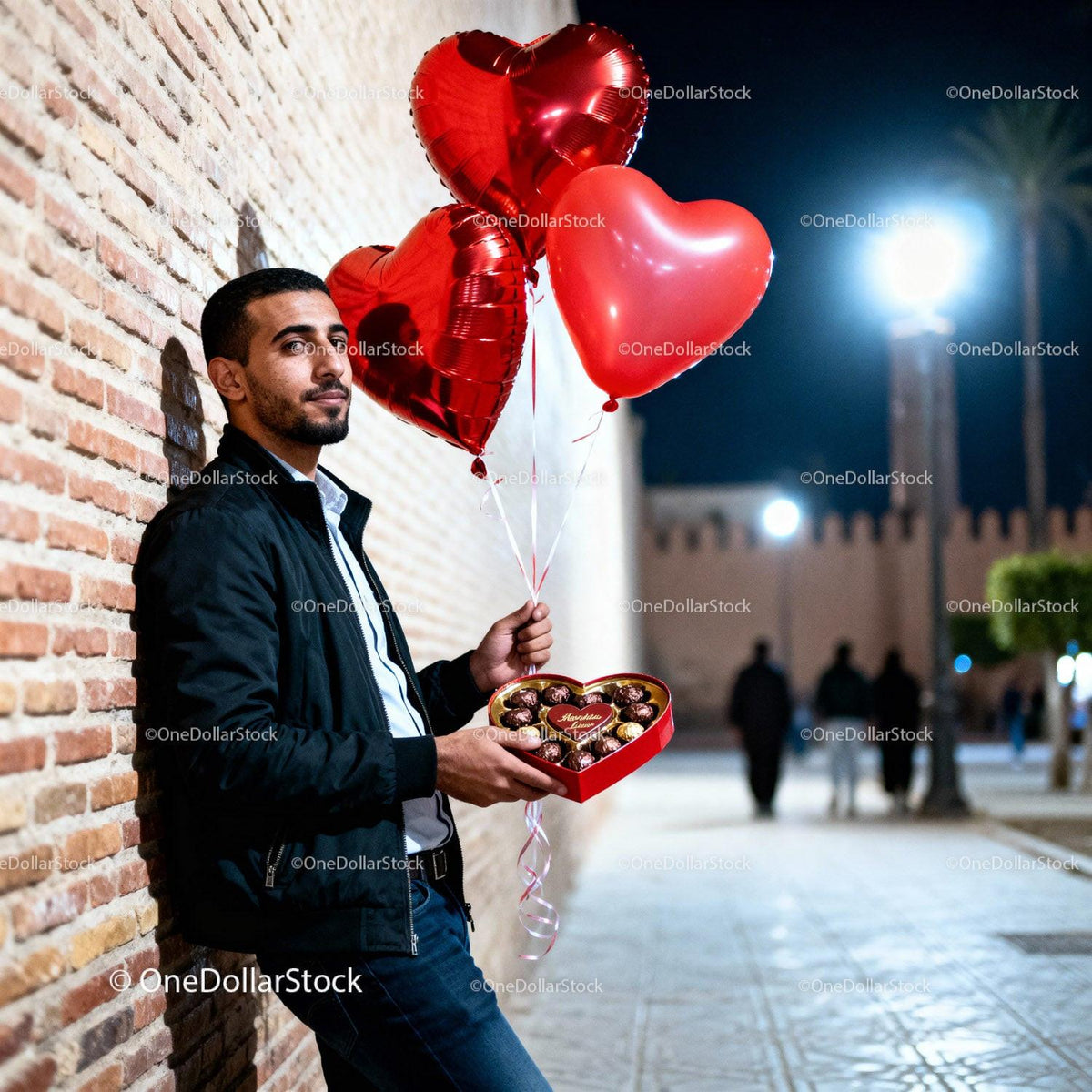 Man holding heart balloons and chocolates at night