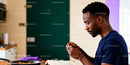 Focused man peeling garlic while reading in kitchen