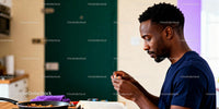 Focused man peeling garlic while reading in kitchen