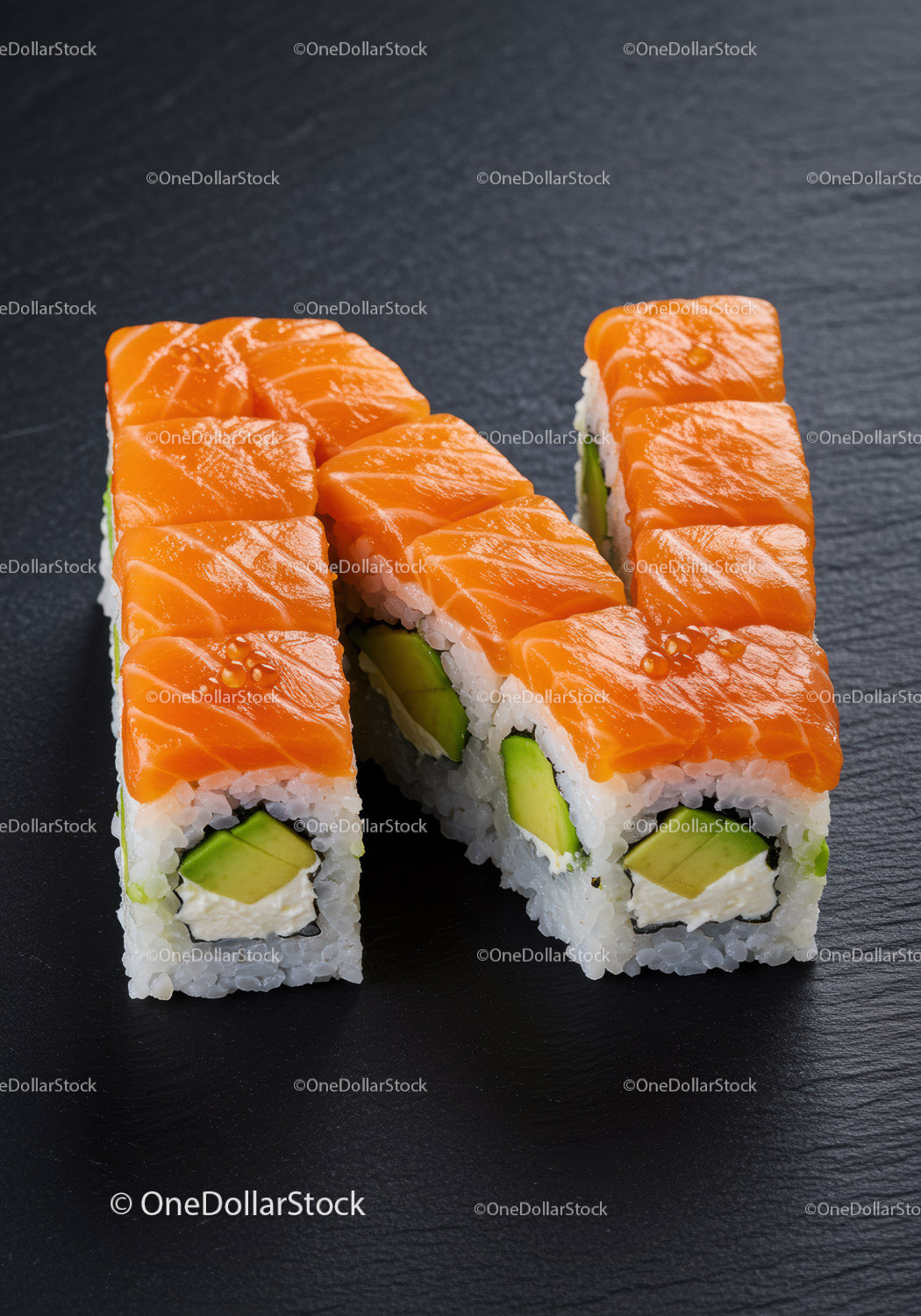 Rolki sushi z łososiem ułożone w literę N na czarnym talerzu