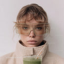 Young Boy with Glasses and Green Smoothie in a Casual Indoor Setting