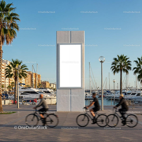 Cyclists riding past blank billboard by marina promenade JPG Mockup Image