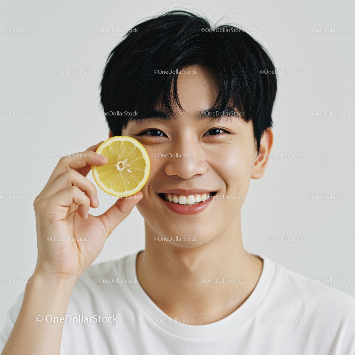 Young Man Smiling Holding Lemon Slice in Bright Casual Portrait