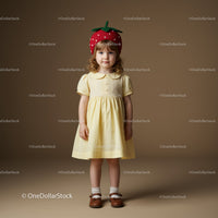 Little girl in yellow dress with strawberry hat