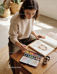 Young woman painting watercolor portrait in cozy space