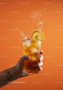 Refreshing iced tea with lemon splash on orange background