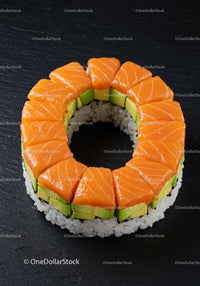 Fresh salmon and avocado sushi ring on black surface