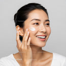 Happy Young Woman Applying Facial Moisturizer for Healthy Skin