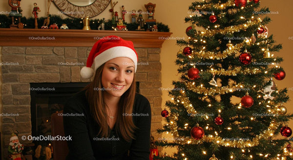 Smiling young woman wearing Santa hat by decorated Christmas tree