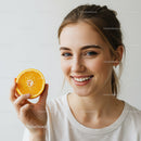 Bright Smiling Woman Holding Orange Slice in Fresh Studio Portrait
