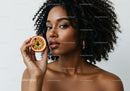 Elegant Woman with Curly Hair Holding Passion Fruit in Studio