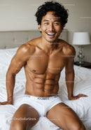 Smiling athletic man in white underwear on bed