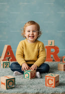 Smiling toddler playing with wooden alphabet blocks