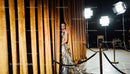 Elegant model emerging from golden velvet curtains