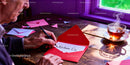 Man writing a love letter in a red envelope at wooden table