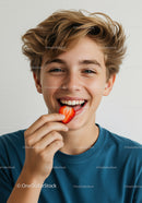 Smiling Teen Eating a Strawberry in Bright Casual Lifestyle Shot