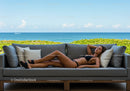 Relaxing Woman Lying on Outdoor Sofa with Sea View and Green Foliage