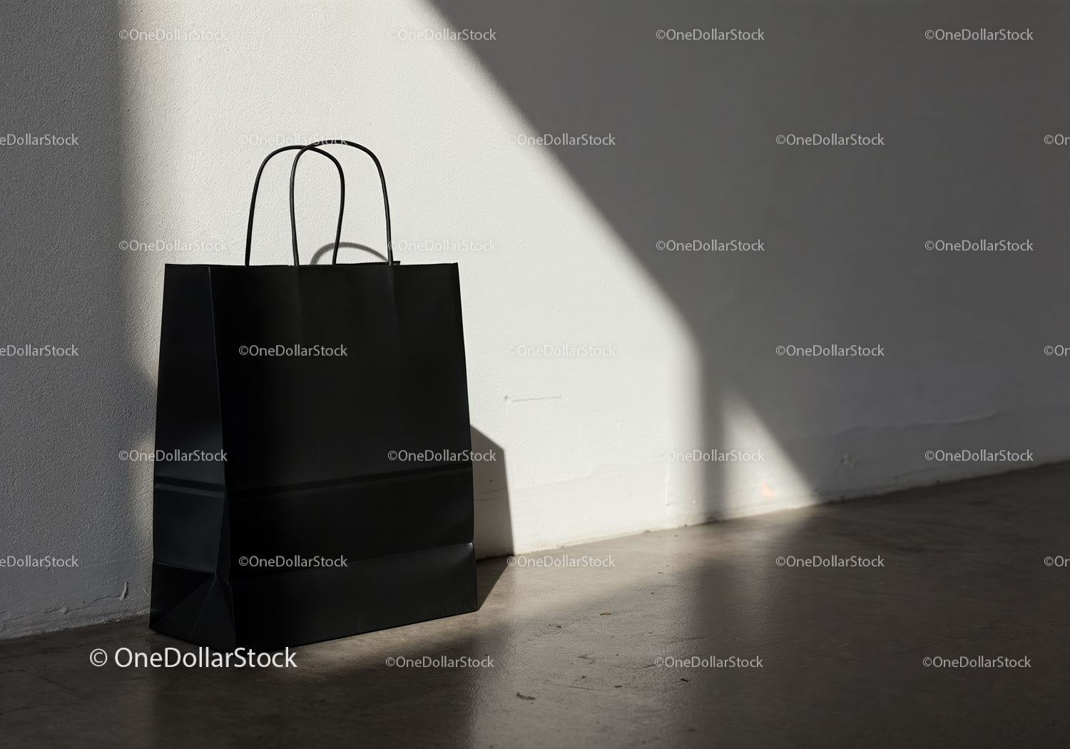 Minimalist black shopping bag on sunlit concrete floor