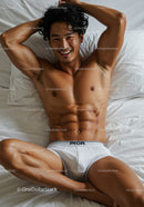 Smiling man relaxing in white briefs on bed