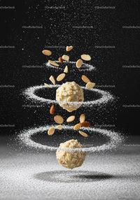 Almond truffles surrounded by swirling powdered sugar