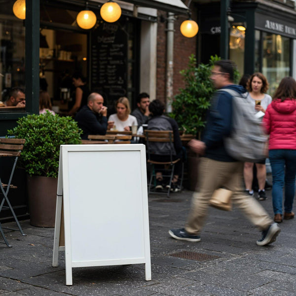 People walking past a cozy outdoor cafe with blank sign JPG Mockup Image