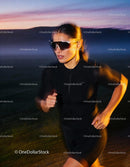 Focused woman running outdoors at dusk in sportswear