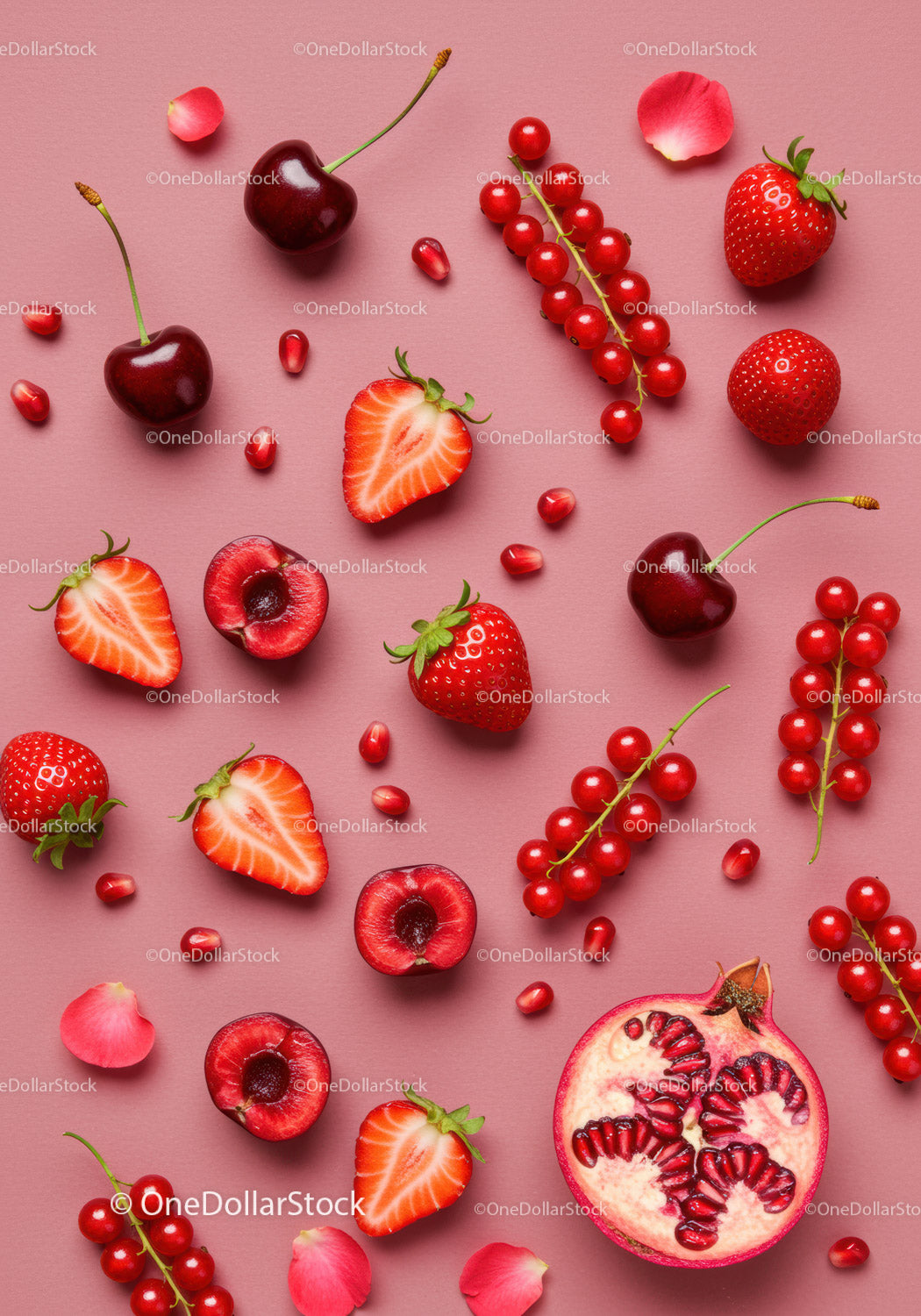 Fresh mixed red berries and pomegranate on pink background