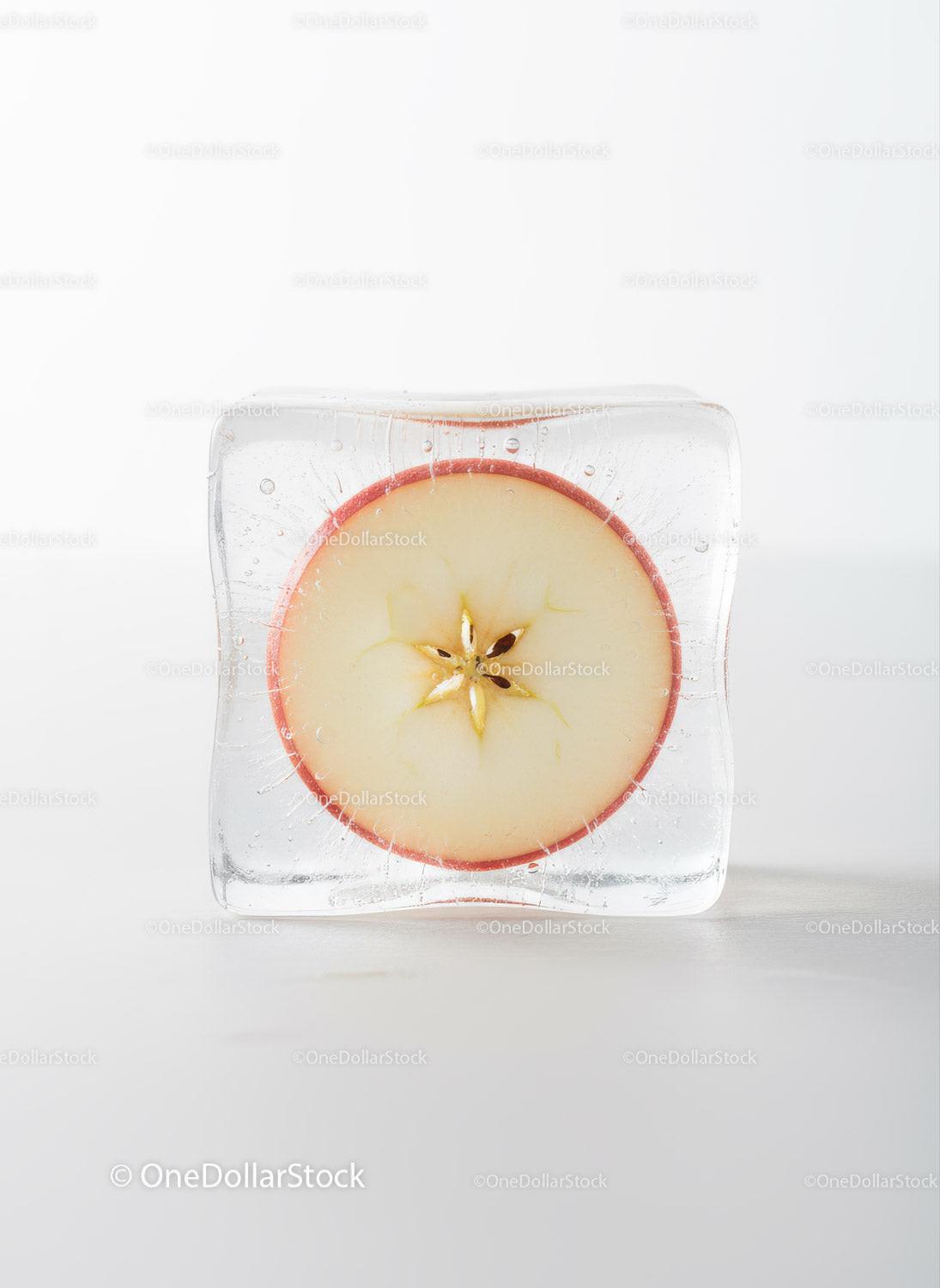 Frozen apple slice captured inside clear ice cube