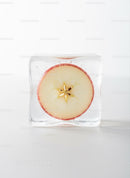 Frozen apple slice captured inside clear ice cube