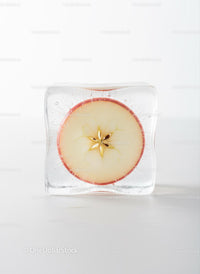 Frozen apple slice captured inside clear ice cube