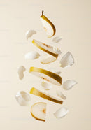 Floating sliced pear with white flower petals on beige