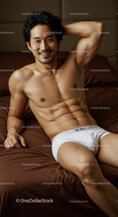 Smiling fit man relaxing on bed in white underwear