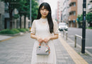 Stylish Woman in White Lace Dress Holding Handbag on City Street