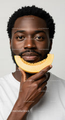 Close-up of a Man with a Melon Slice in a Bright Minimalist Studio