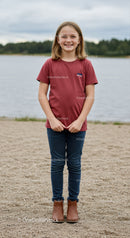 Smiling Girl in Casual Red T-Shirt and Jeans Standing by Lake