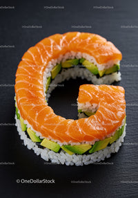 Fresh salmon sushi roll shaped as letter G on black plate