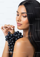Elegant Woman with Black Hair Holding Bunch of Fresh Black Grapes