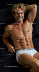 Smiling muscular man relaxing on black bedding