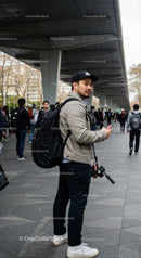 Stylish Young Man with Backpack Using Smartphone in City Street
