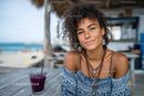 Smiling Woman with Curly Hair Enjoying Seaside Cafe Scene