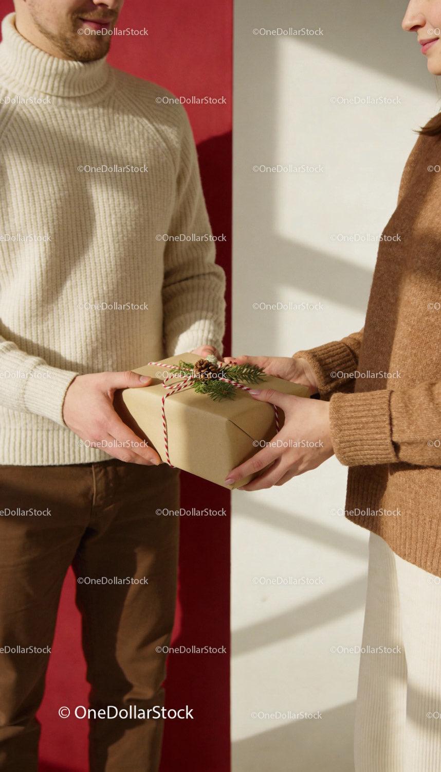 Two People Exchanging A Festive Wrapped Gift
