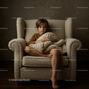 Thoughtful boy sitting on armchair with knitted blanket