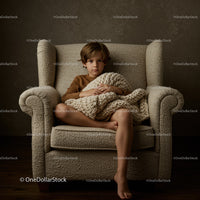 Thoughtful boy sitting on armchair with knitted blanket