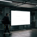 Man walking past illuminated billboard in parking garage