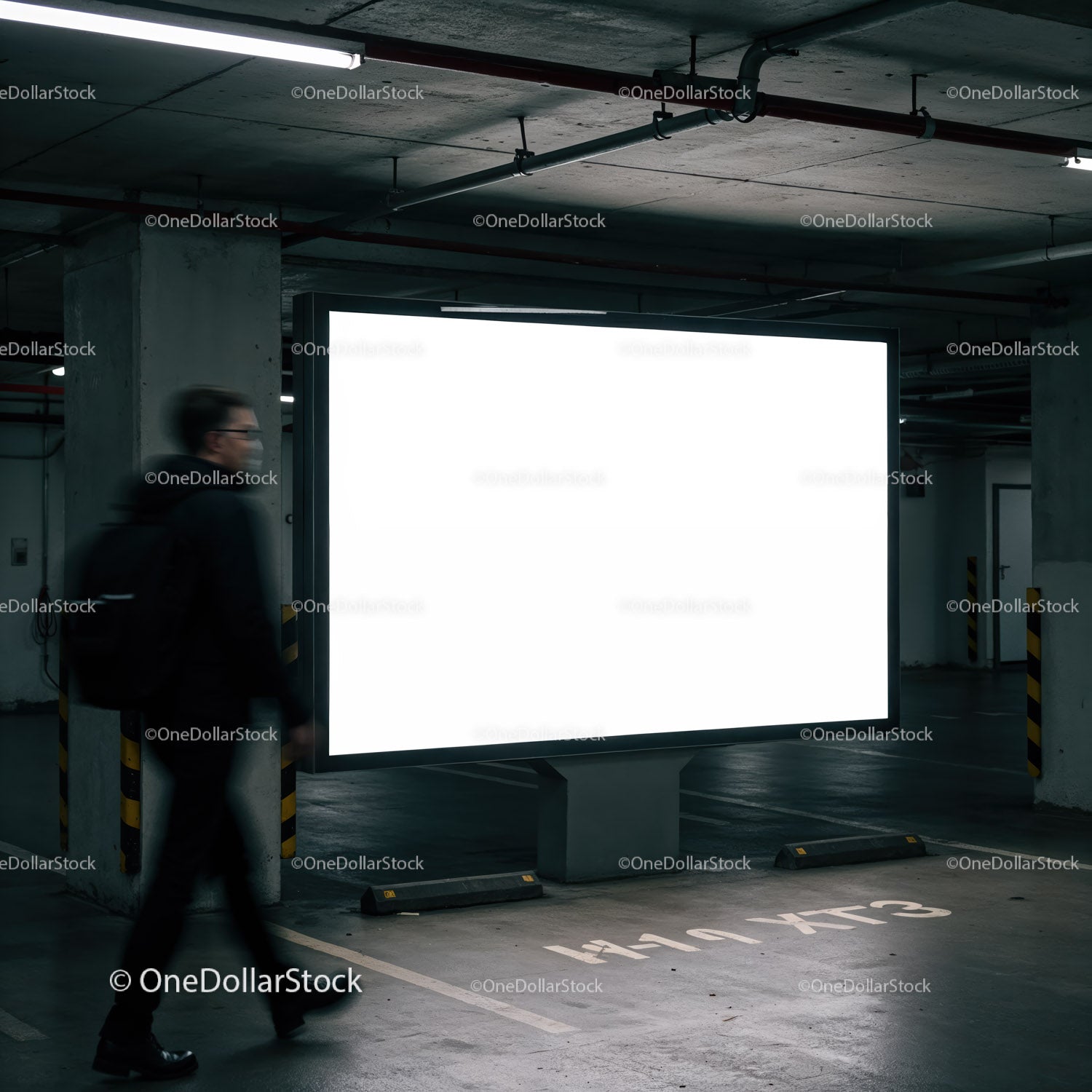 Mężczyzna przechodzący obok oświetlonego billboardu w garażu