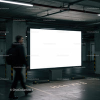 Man walking past illuminated billboard in parking garage