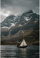 Sailboat cruising near misty snow-capped mountains
