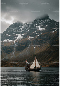 Sailboat cruising near misty snow-capped mountains