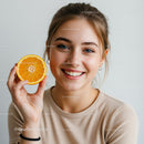 Smiling Woman Holding Fresh Orange Slice in Bright Portrait