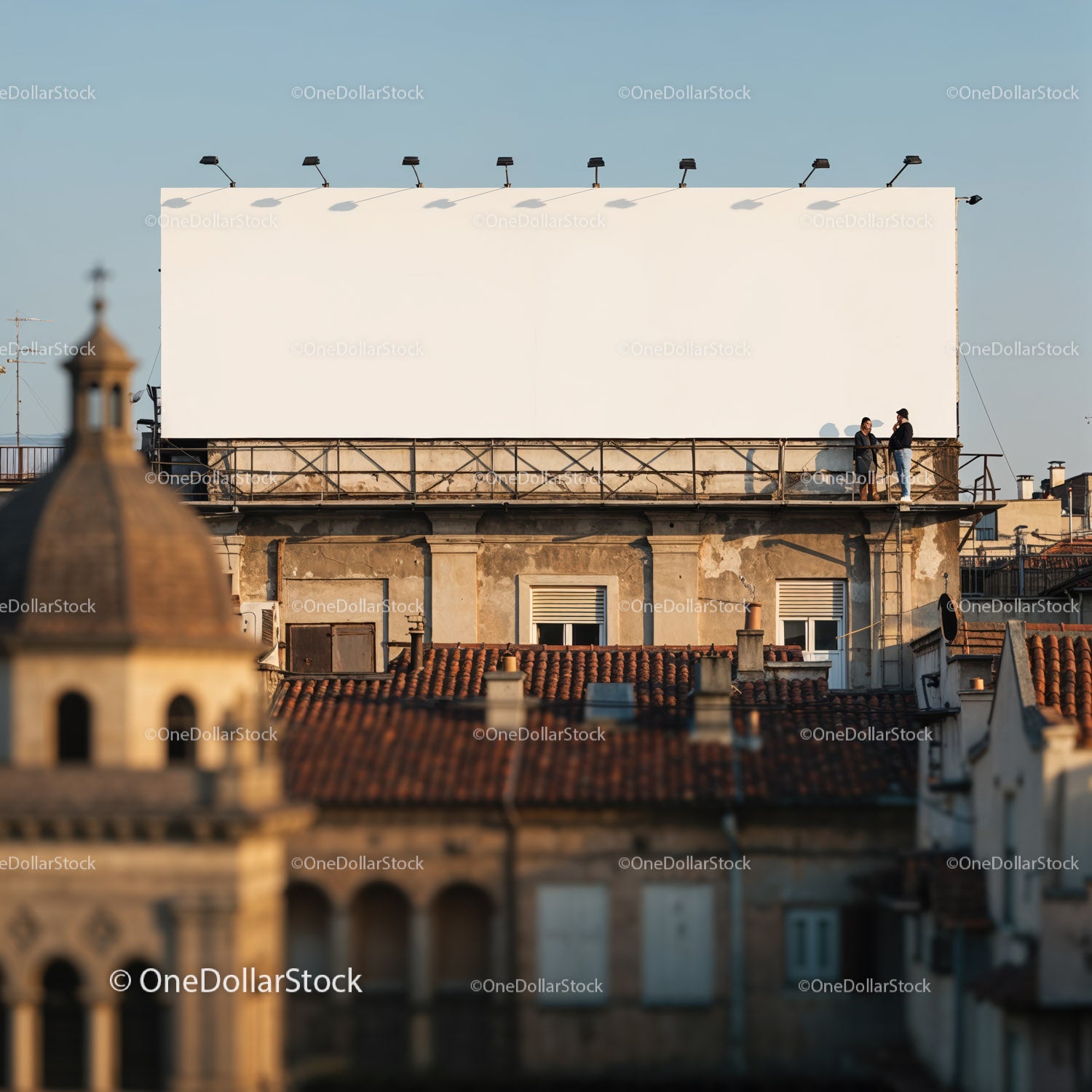 Two men standing near large blank billboard on rooftop